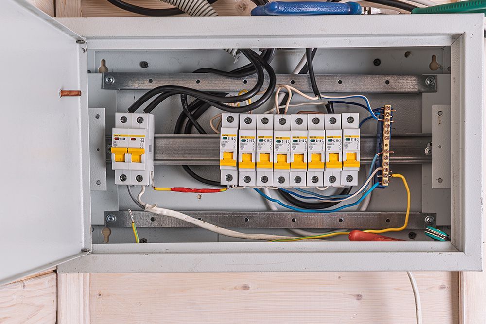 Open electrical breaker panel with wires and circuit breakers inside a wall-mounted cabinet