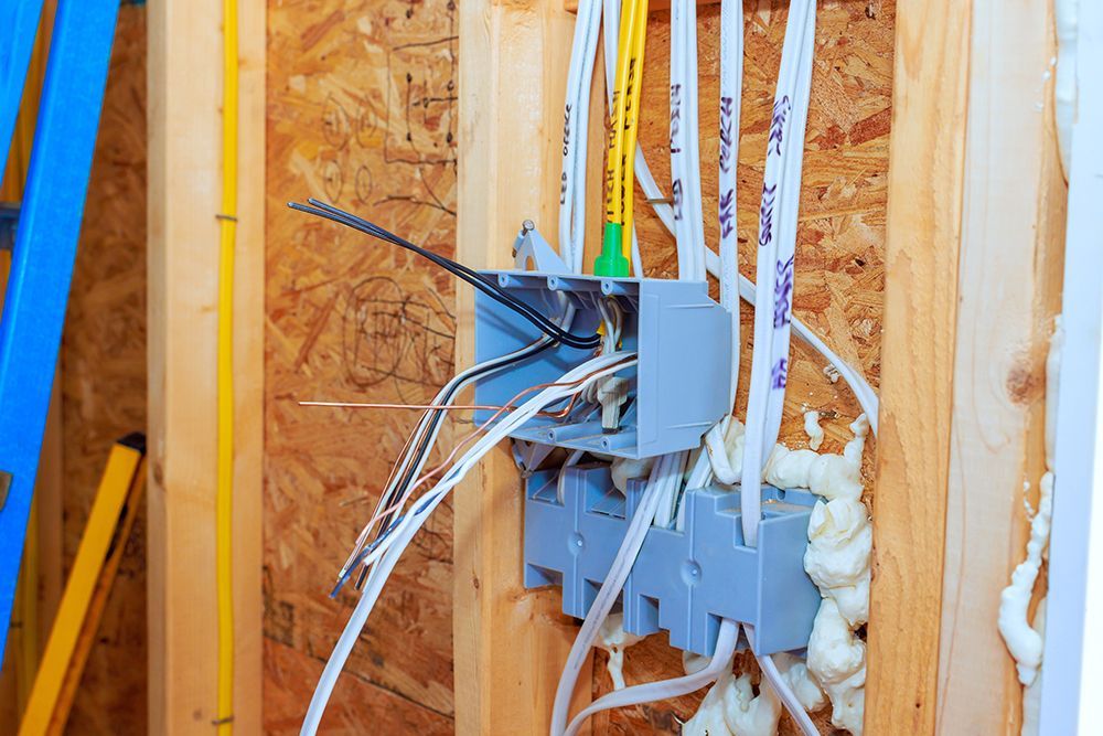 Electrical wiring and outlets in an unfinished wall, with exposed cables and foam insulation.