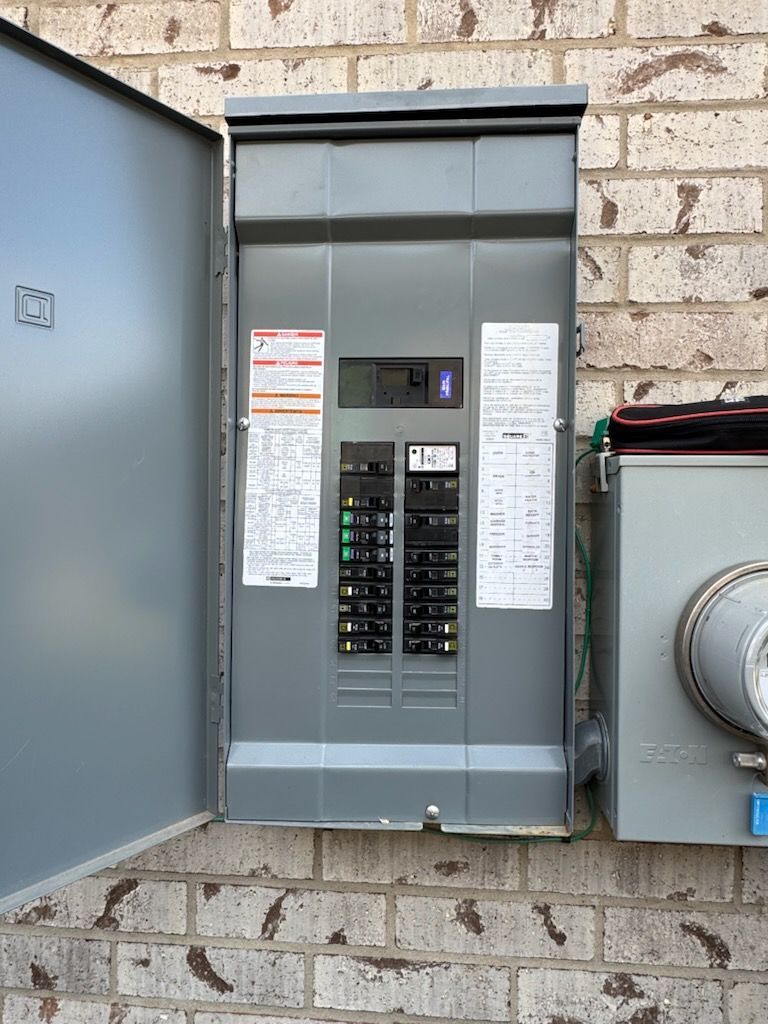 Open electrical meter and breaker panel mounted on a brick wall outdoors