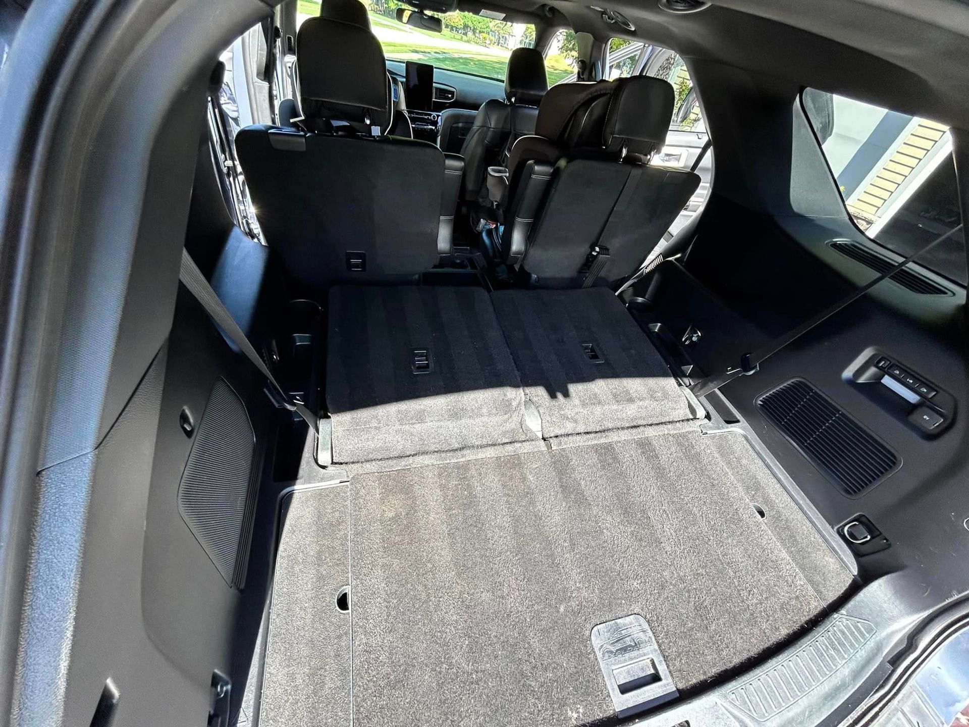 Folded-down rear seats in a vehicle, creating a flat cargo area with black upholstery and side panels.