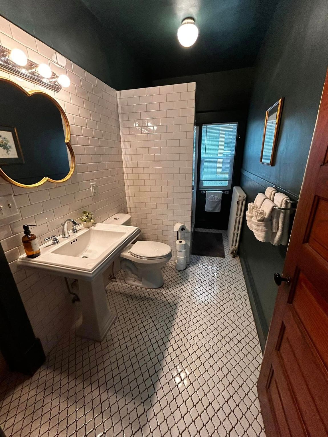 Small tiled bathroom with sink, toilet, mirror, shower, and blue walls.