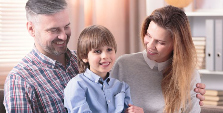 Three people smiling in a bright kitchen, with a child in a blue shirt between two adults. — PoDDSS in Townsville, QLD