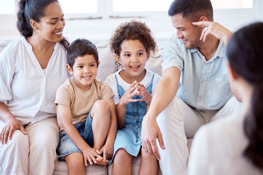 Family sitting together on a couch, smiling and talking in a bright living room. — PoDDSS in Hyde Park, QLD