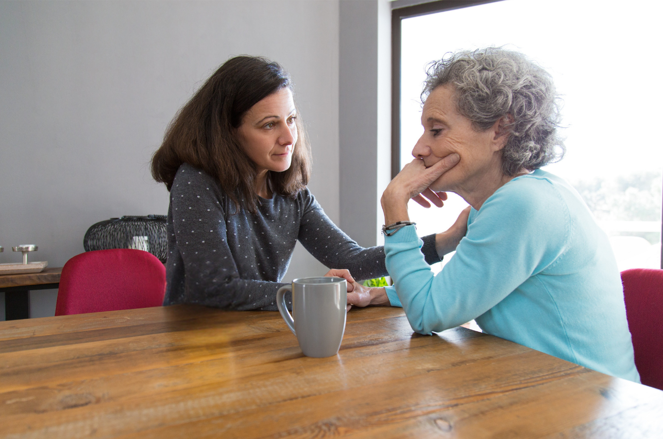 Two people talking at a wooden table with a mug in a bright room — PoDDSS in Mount Isa, QLD