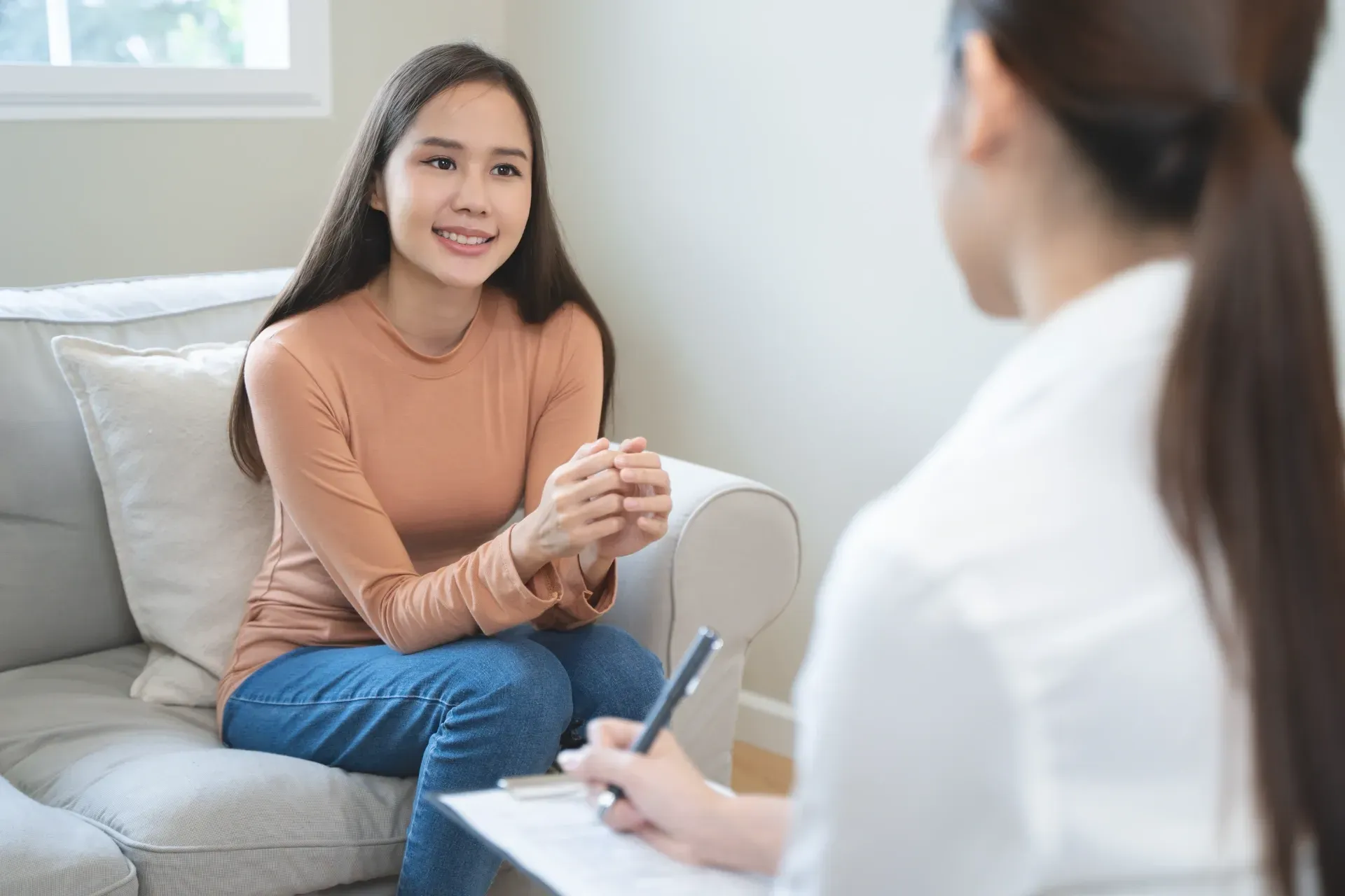 Counselor speaking with a smiling client on a sofa in a bright office — PoDDSS in Charters Towers, QLD