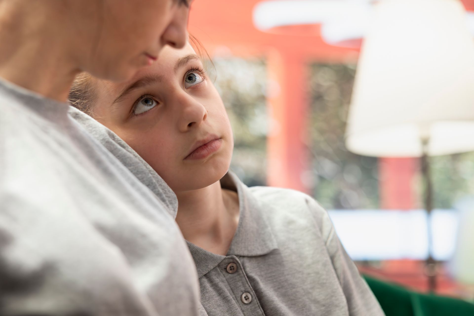 Child leaning against an adult indoors, looking up with a thoughtful expression — PoDDSS in Charters Towers, QLD