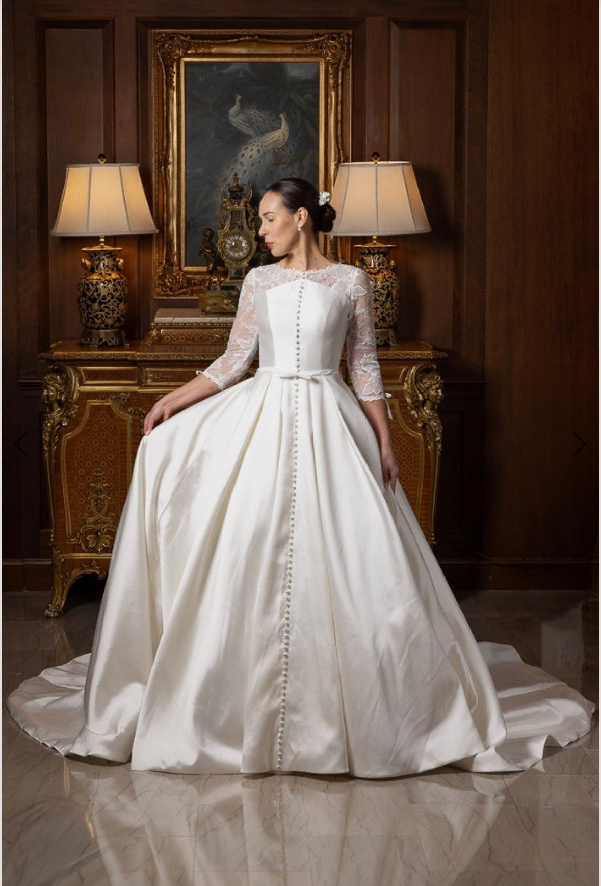 Woman in a white strapless mermaid gown posing indoors by large windows.