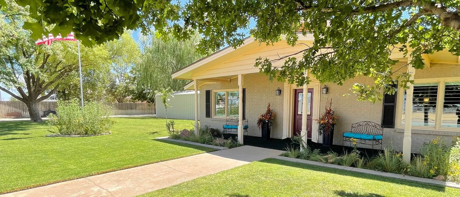 The front door of a house with a porch and plants in front of it.