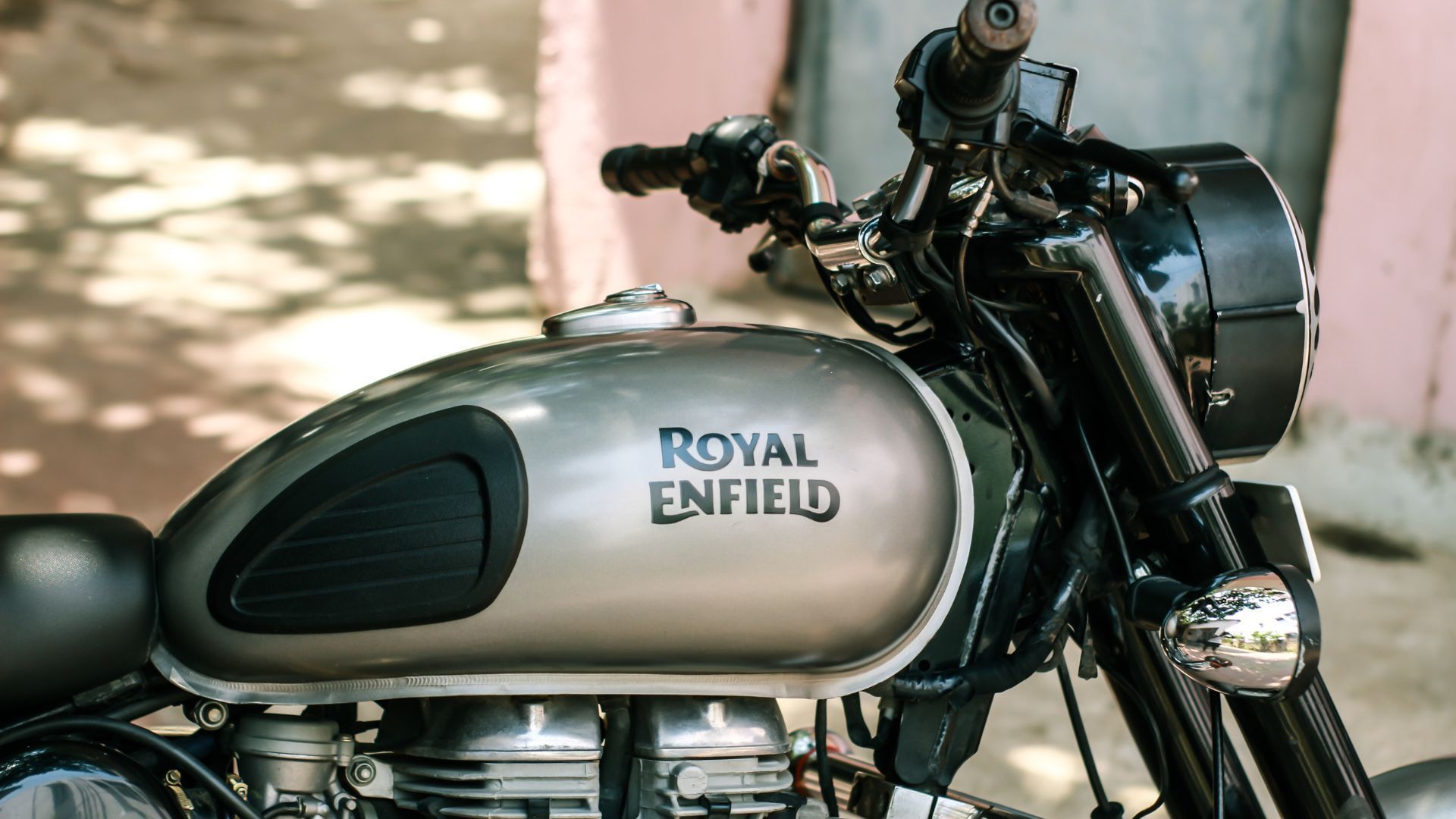 Two motorcycles parked side by side against a brick wall on cobblestone pavement.