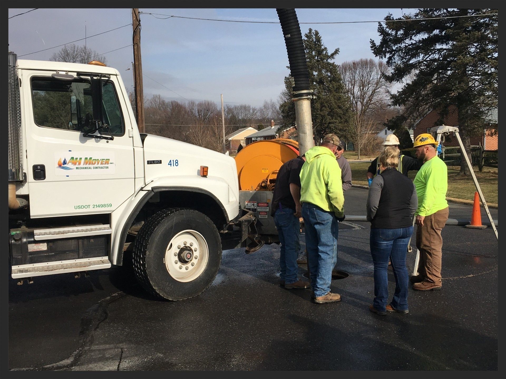 Utility crew working beside a white truck and orange equipment on a wet roadside