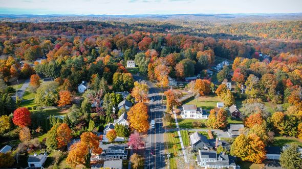 Aerial view of a suburban neighborhood with autumn trees in vivid orange, red, and yellow colors.