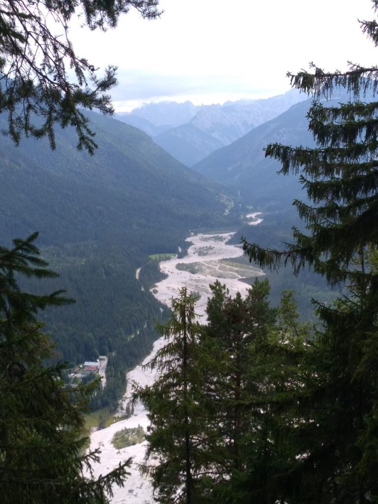 Ausblick von oben auf einen Fluss mit vielen Flussschleifen, daneben hohe Berge