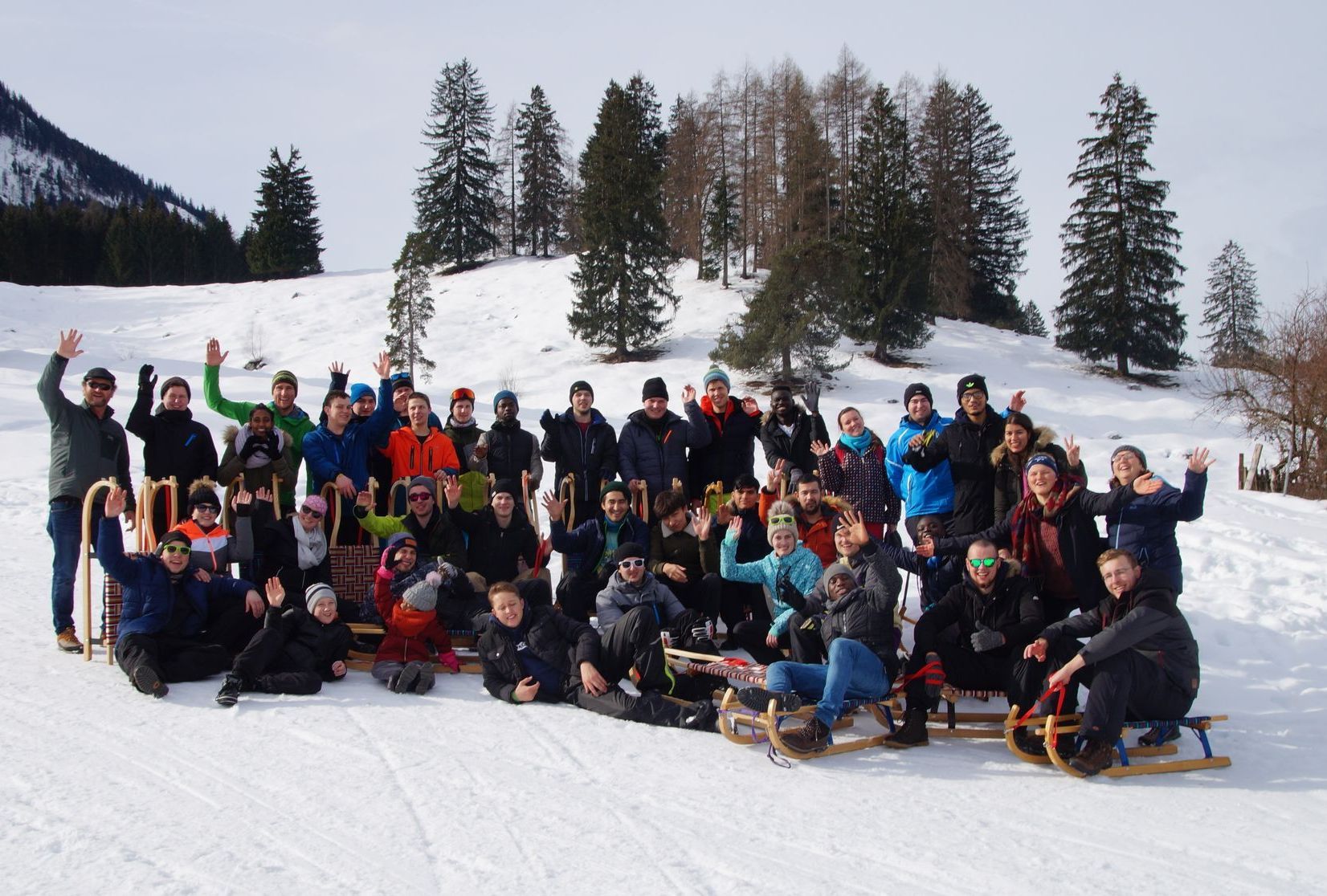 Gruppenfoto mit vielen Jugendlichen, teils auf Schlitten, im Schnee