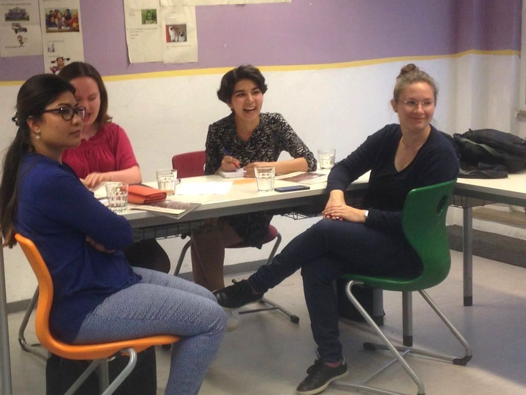 4 junge Frauen um einenn Tisch mit Schreibutensilien