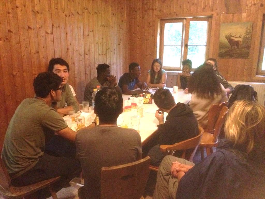 Junge Menschen um einen Tisch in Berghütte - Abendstimung
