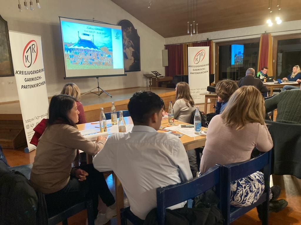 Menschen sitzen im Saal und schauen auf Powerpoint