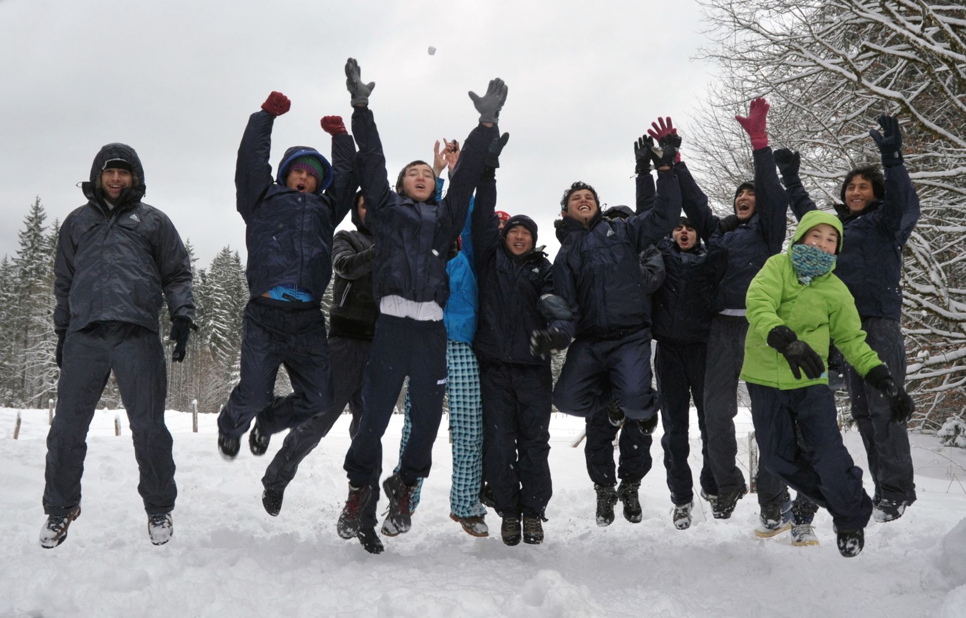 Junge Menschen springen jubelnd im Schnee