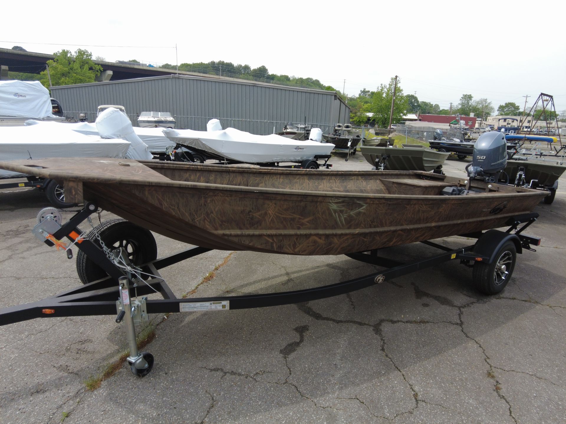 A boat is sitting on a trailer in a parking lot.