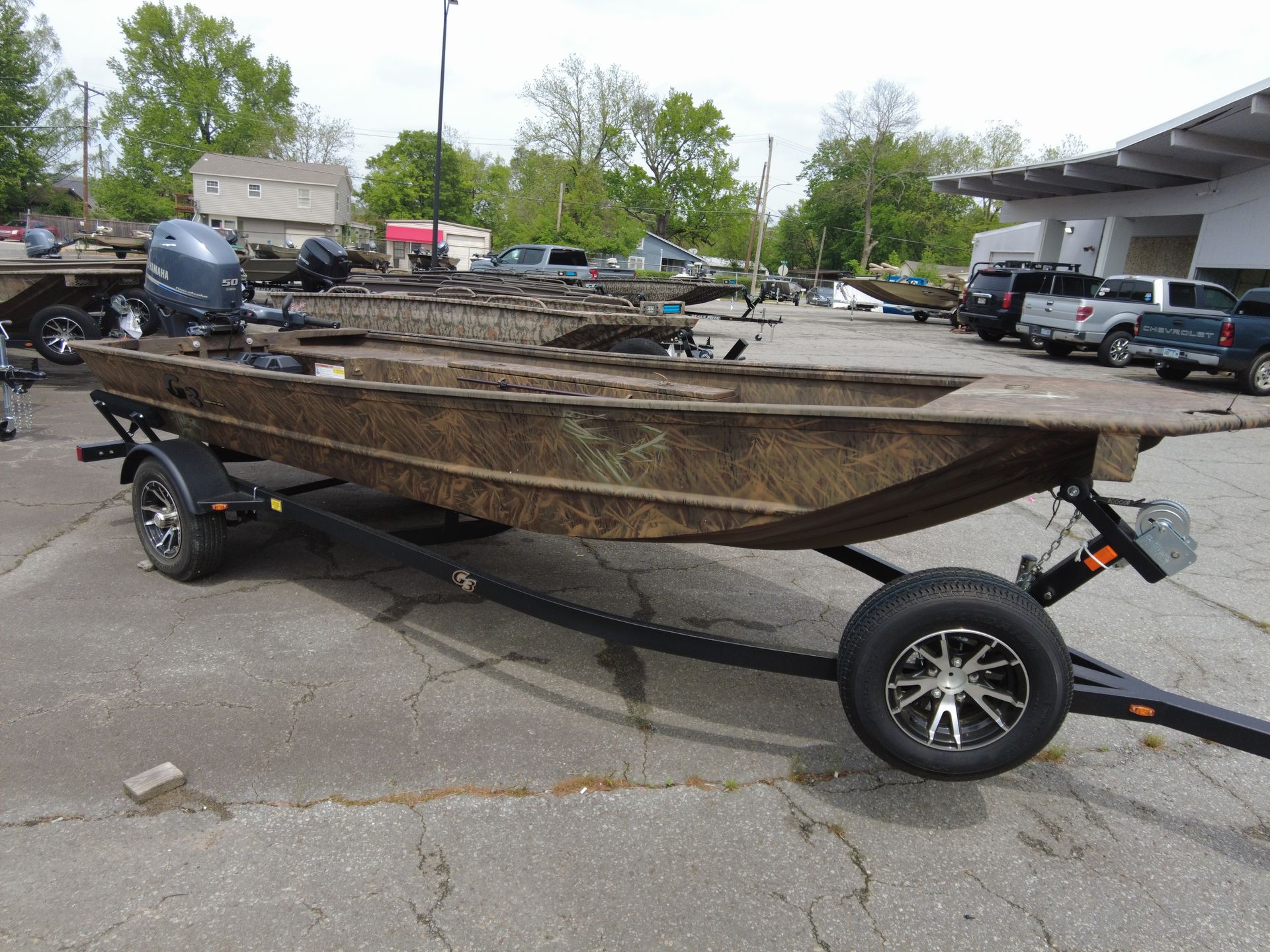A boat is sitting on a trailer in a parking lot.