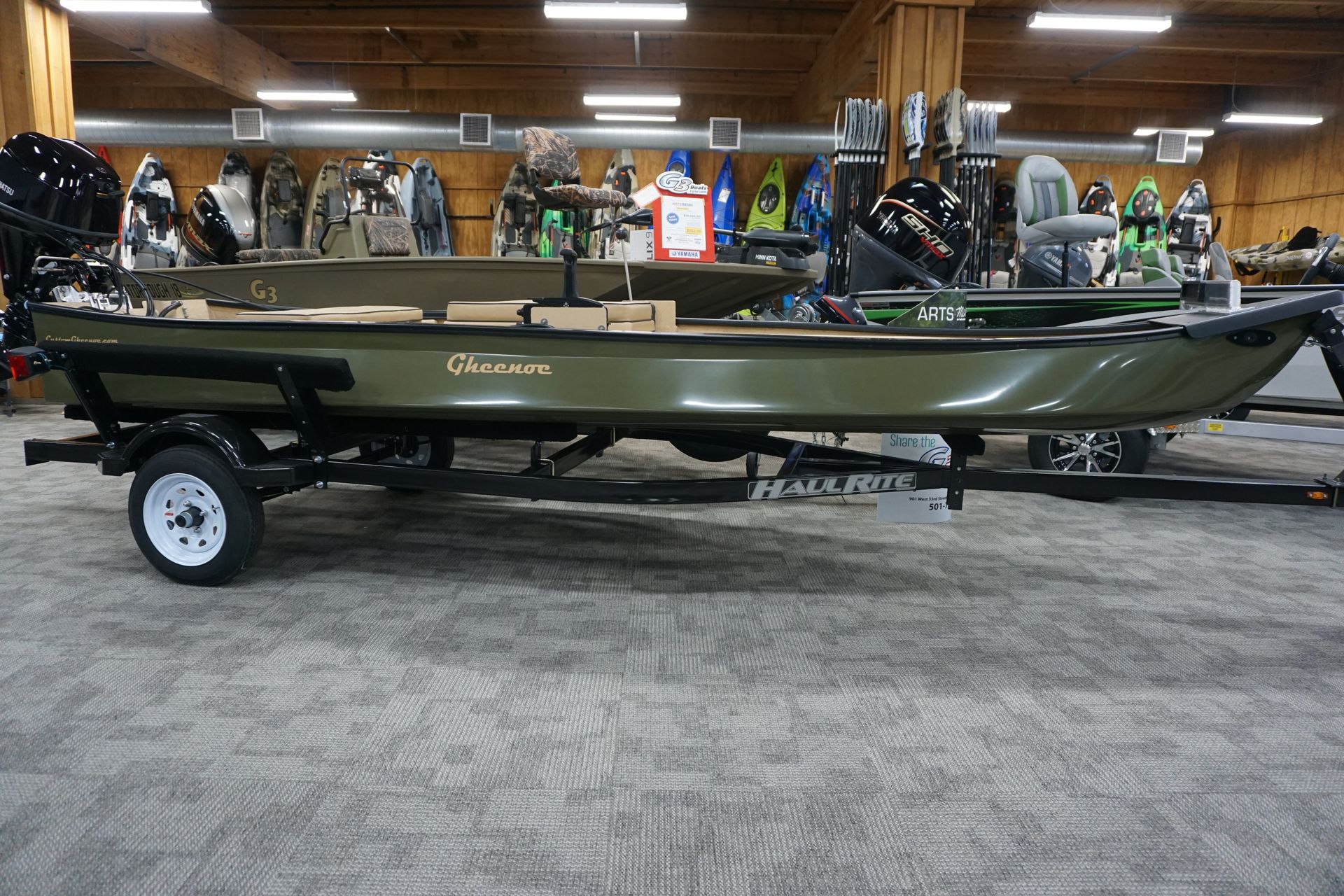 A green fishing boat is on a trailer in a store.