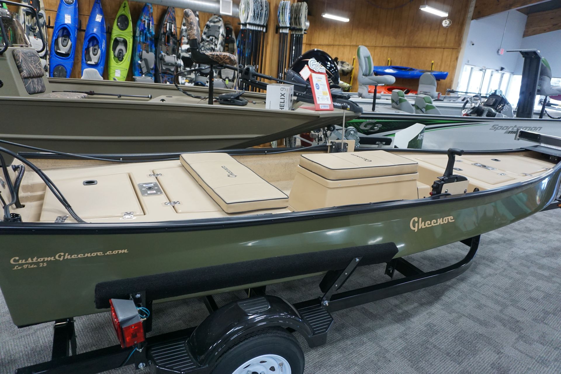 A green boat is sitting on a trailer in a store.