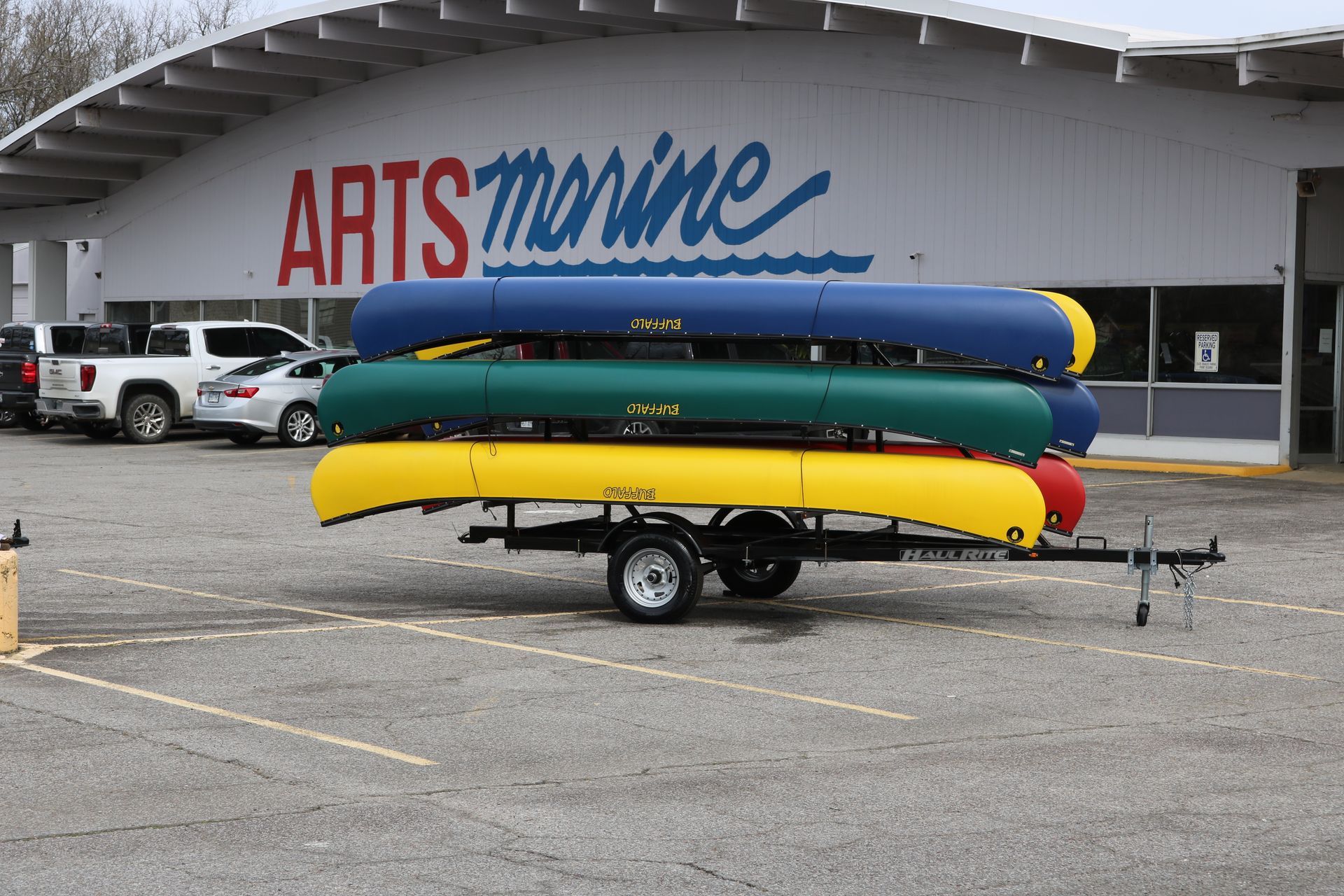A row of canoes on a trailer in front of a arts marine store