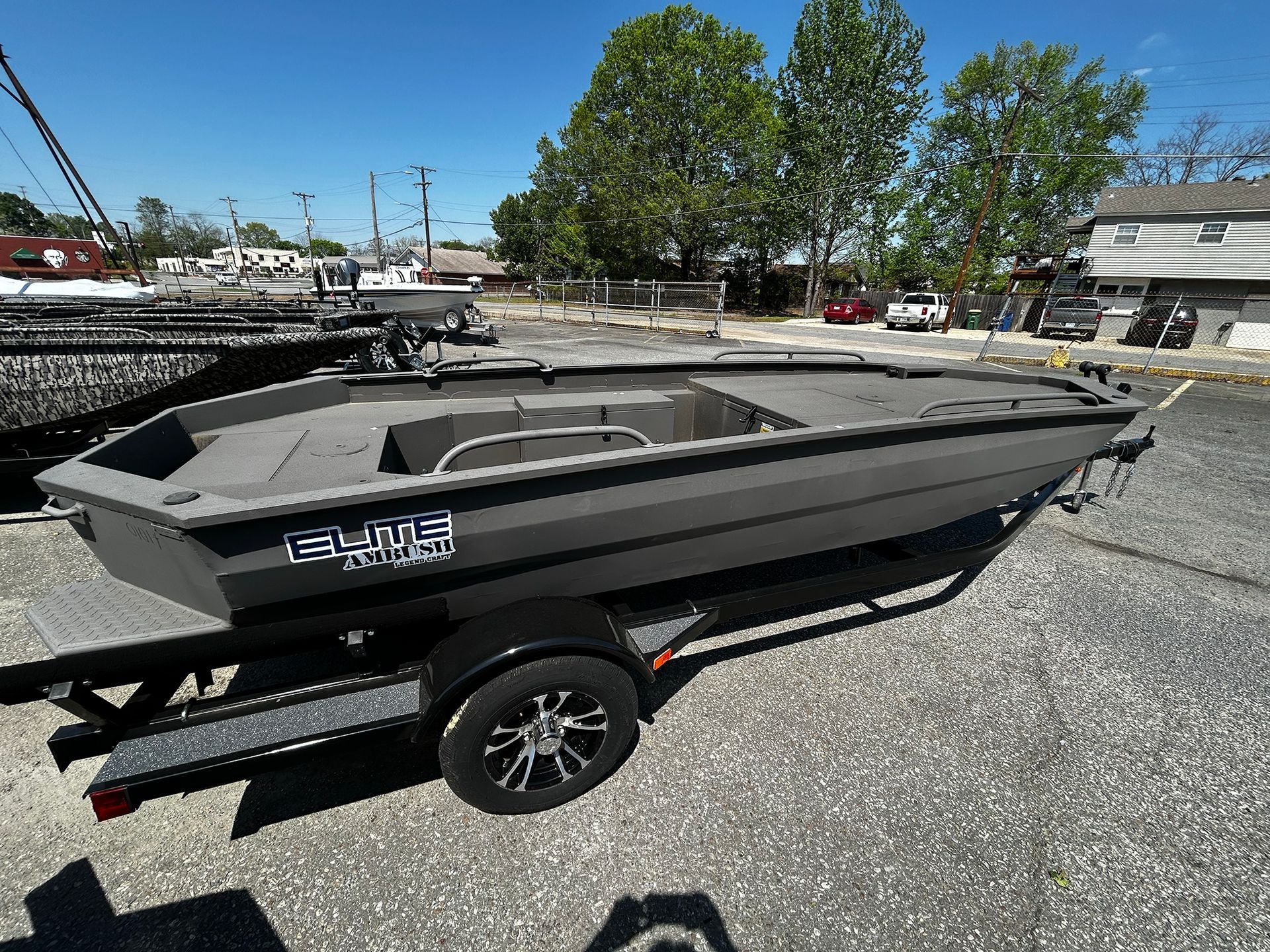 A small boat is on a trailer in a parking lot.