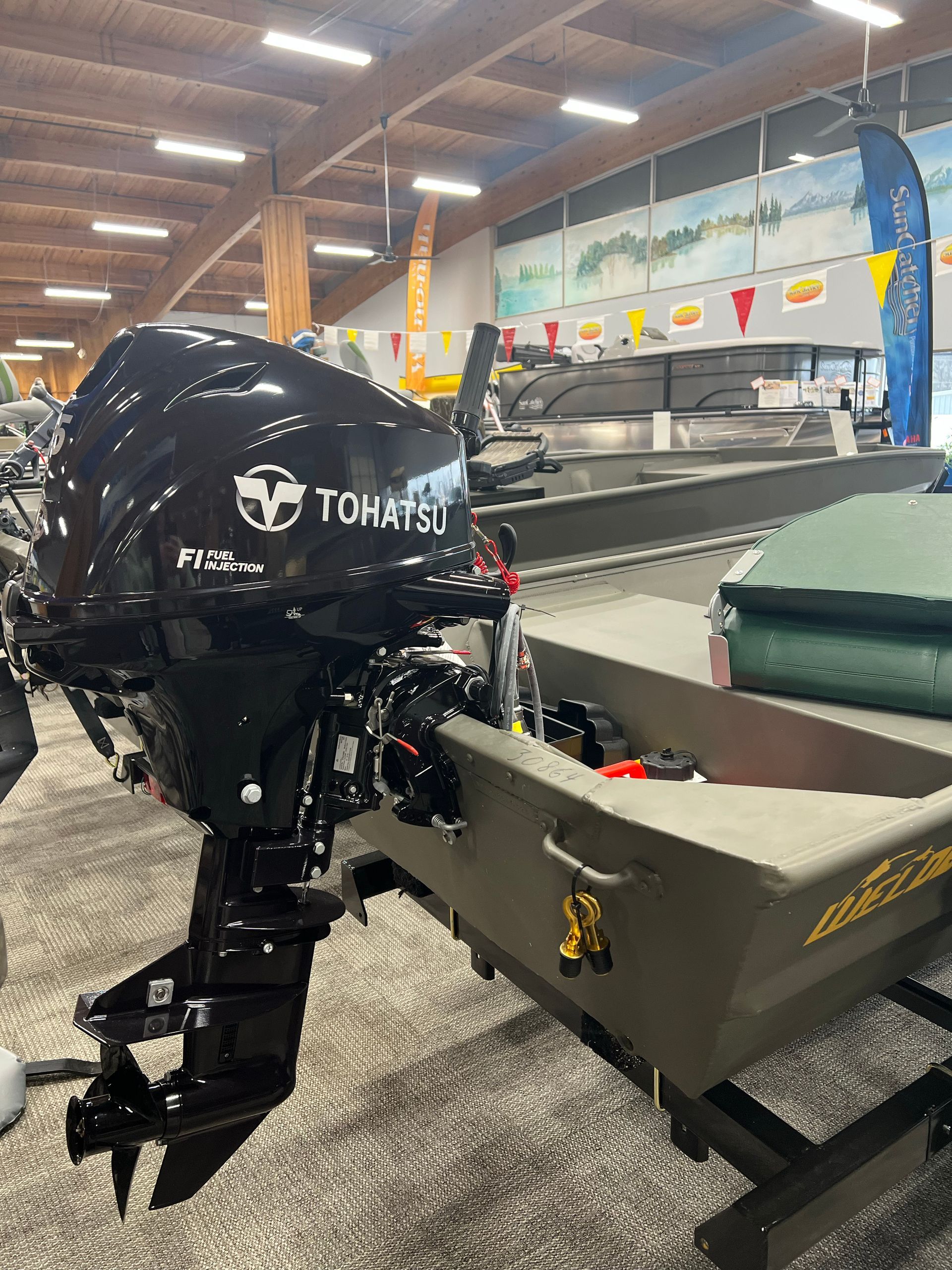 A black outboard motor is sitting on top of a boat in a showroom.