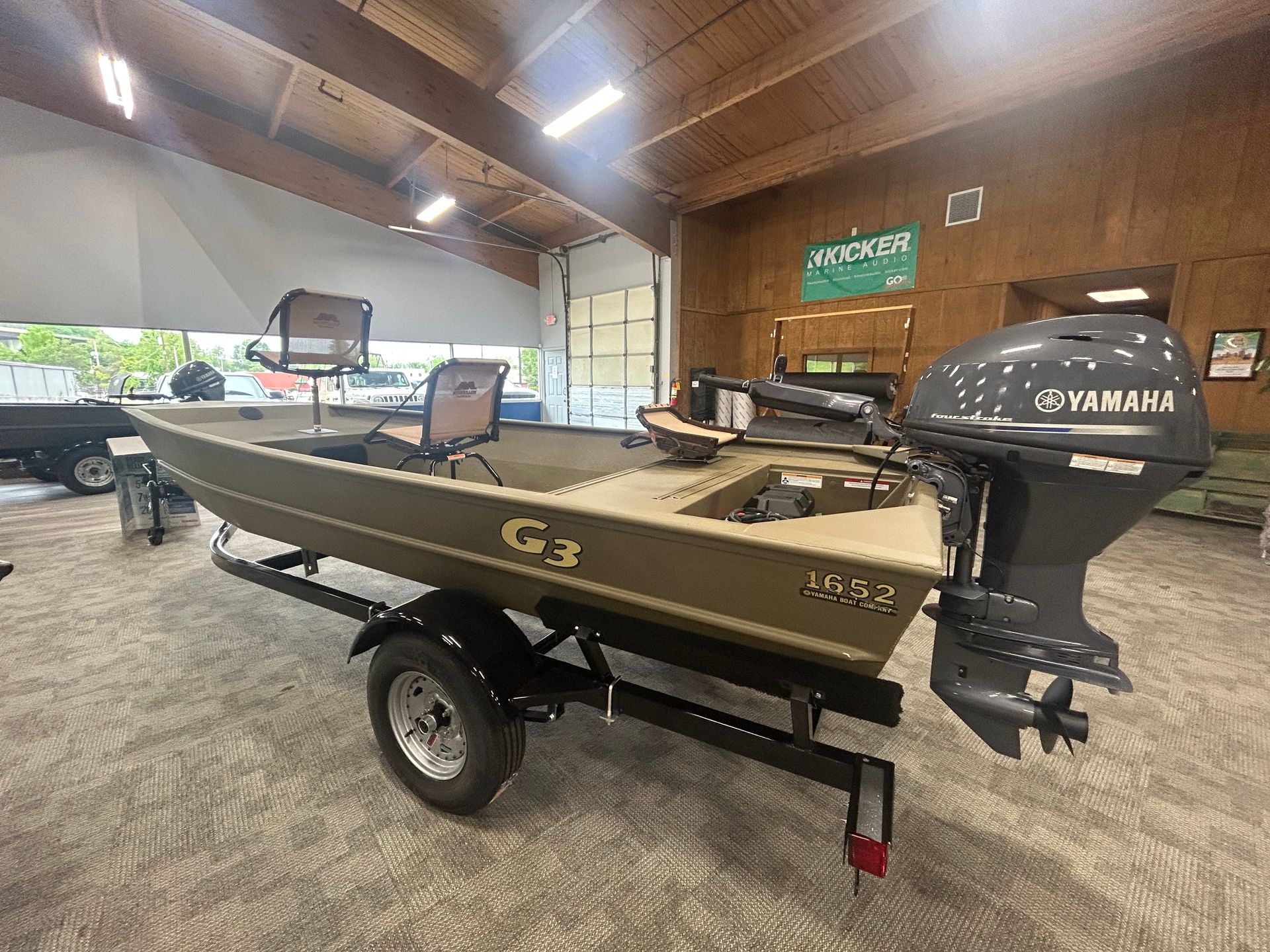 Small fishing boat on a trailer in a garage, with a Yamaha outboard motor and open bay doors.