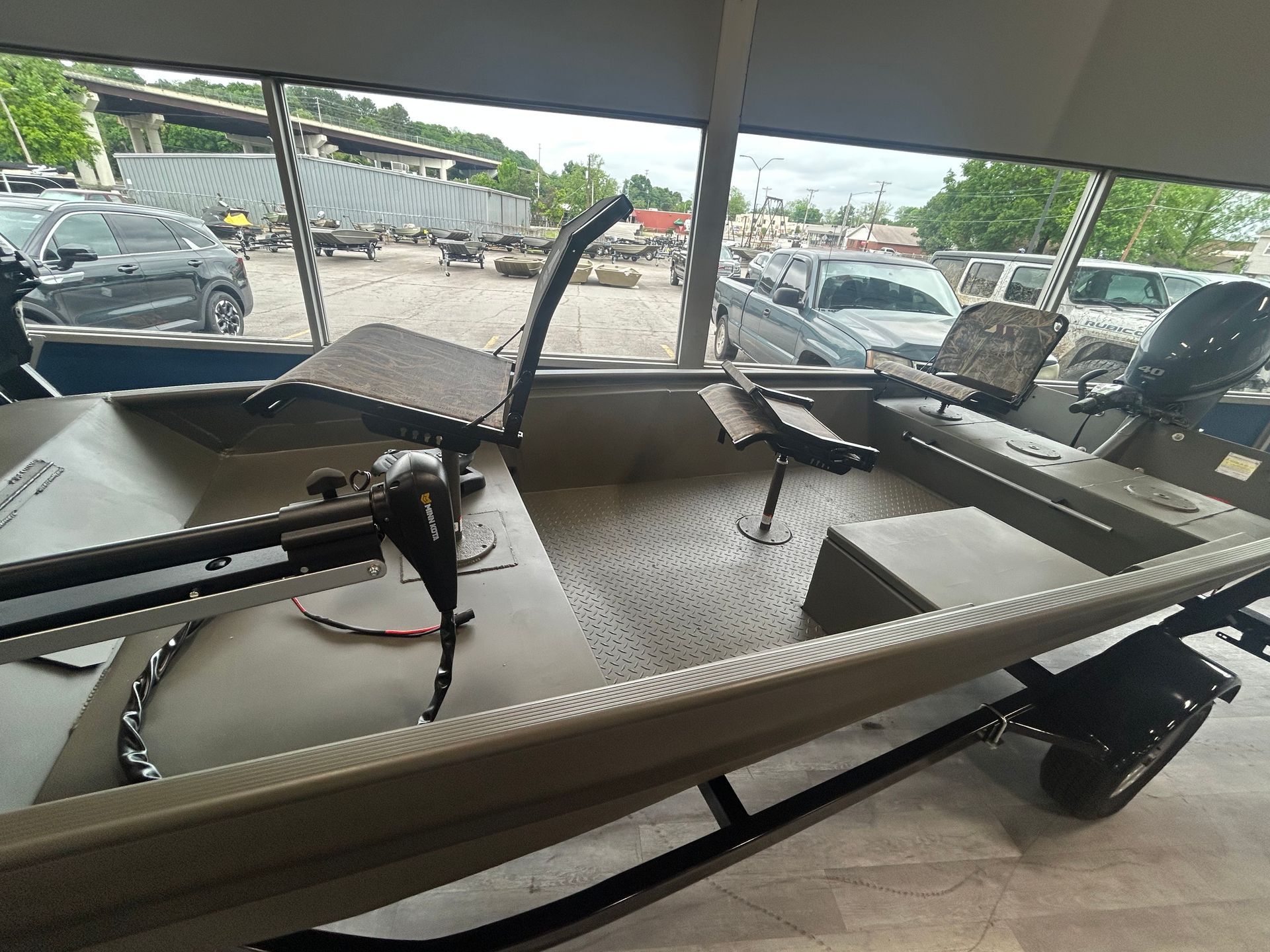 Empty boat trailer under a covered parking area, with parked cars in the background.