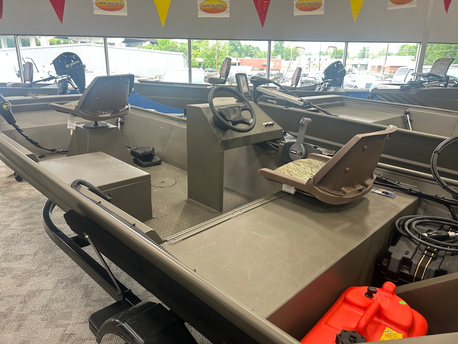 Gray metal utility boat with center console and seats, shown indoors with an orange fuel can in the foreground