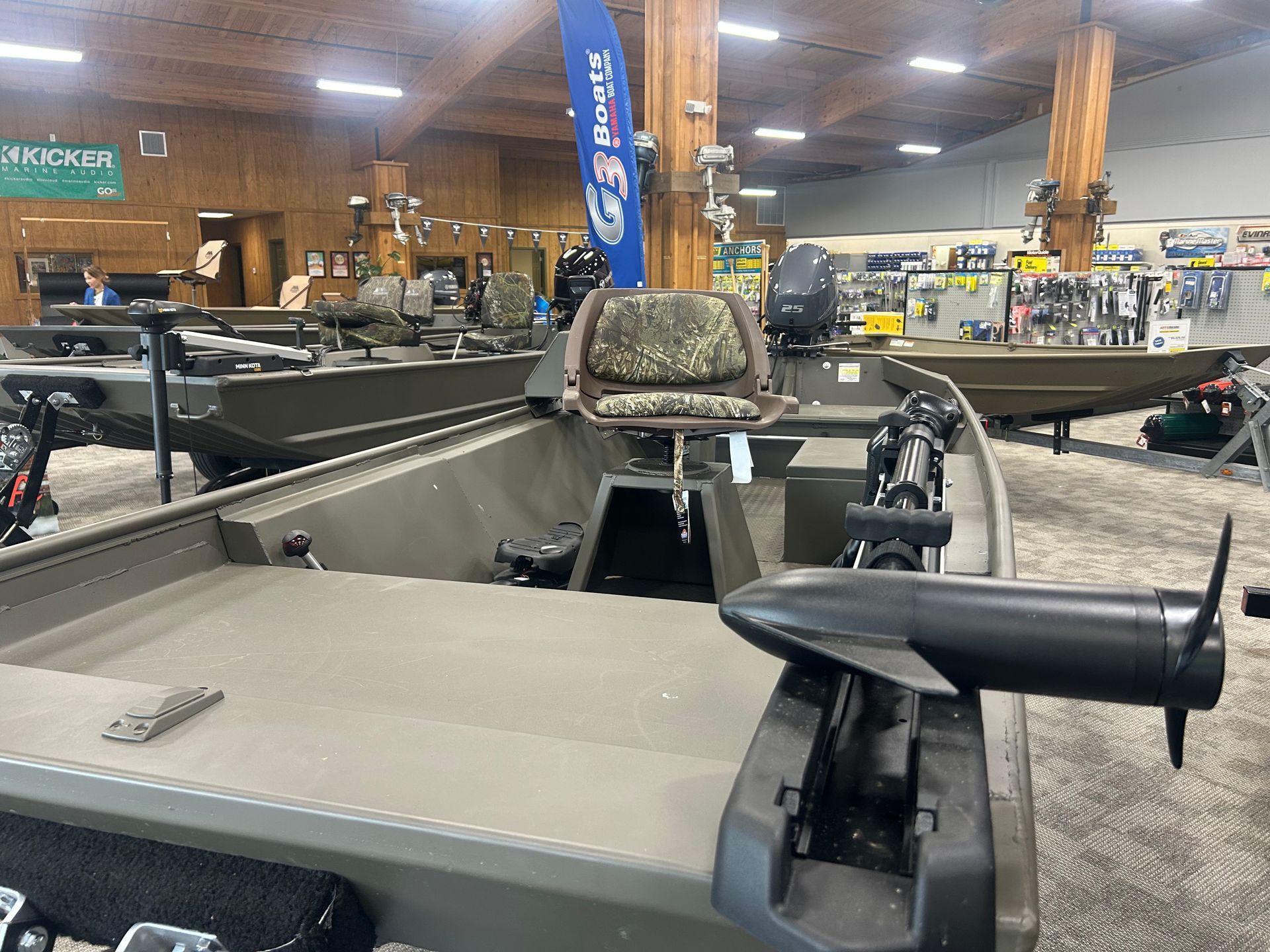 Fishing boat display inside a showroom with rows of boats and overhead lights.
