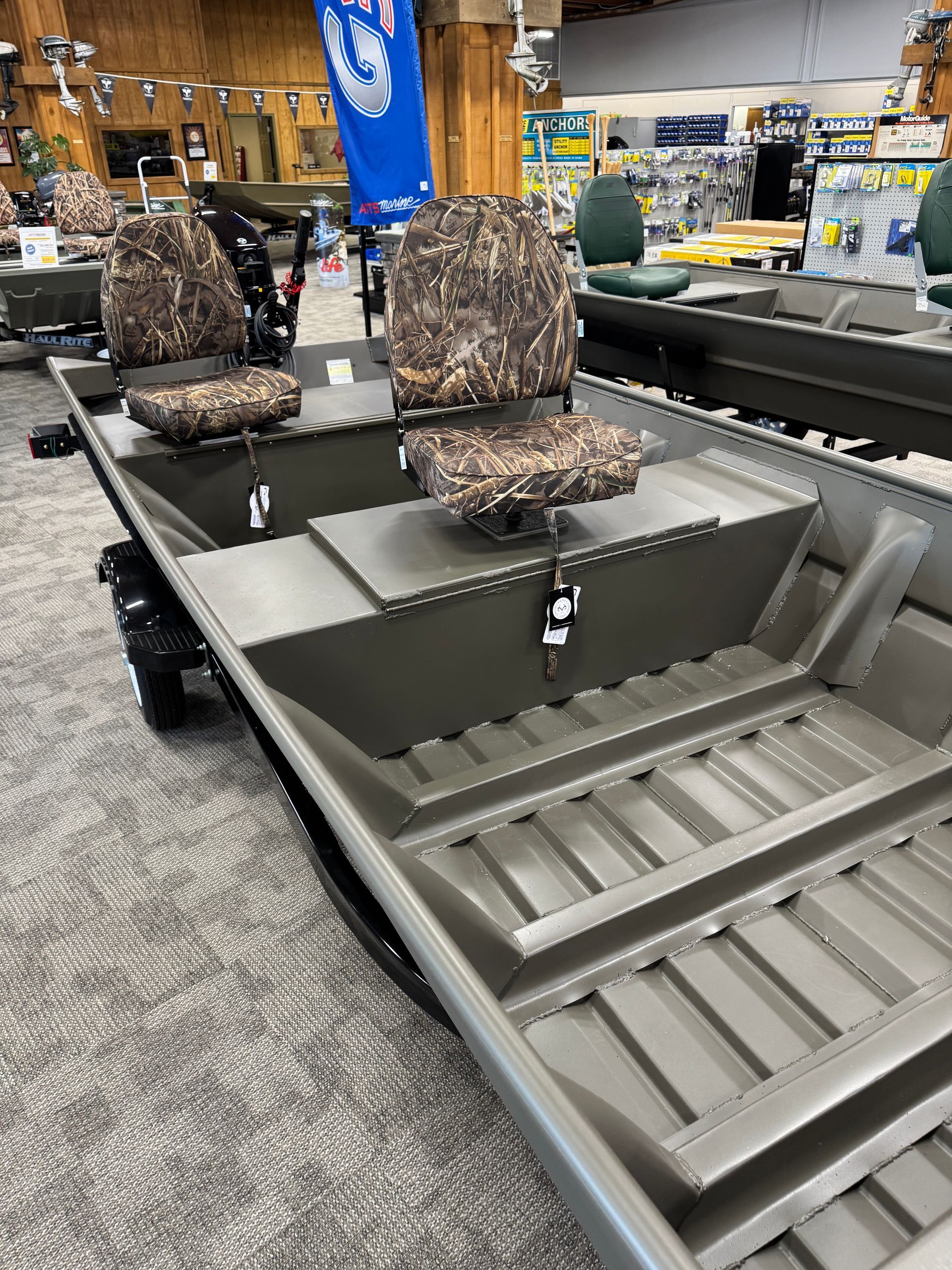 Two camo-patterned seats in a gray metal duck boat on display in a store