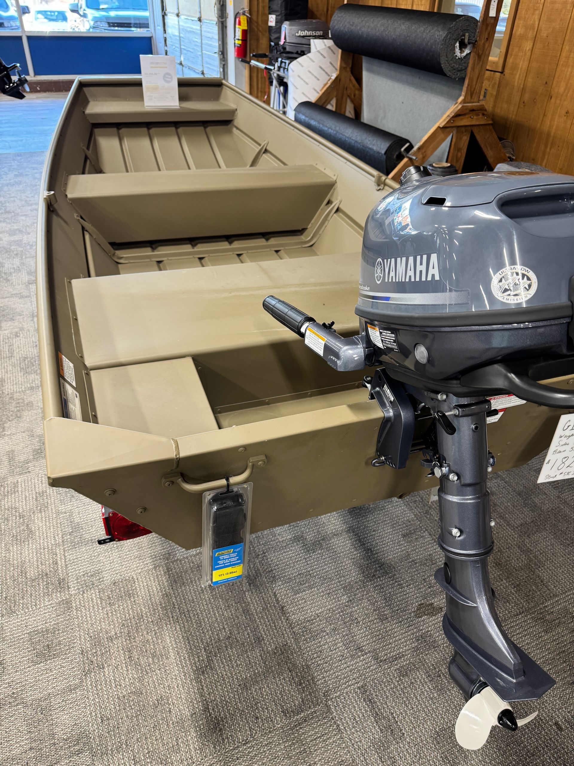 Tan flat-bottom fishing boat with Yamaha outboard motor inside a showroom