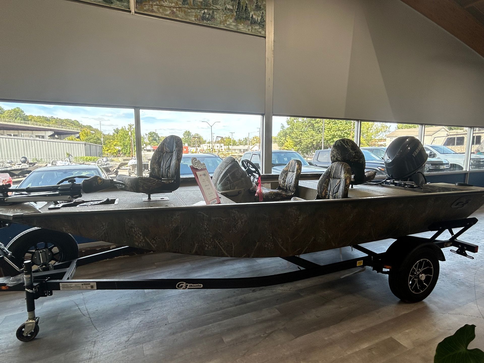 Black fishing boat on a trailer under a covered dock, with motors and gear aboard.