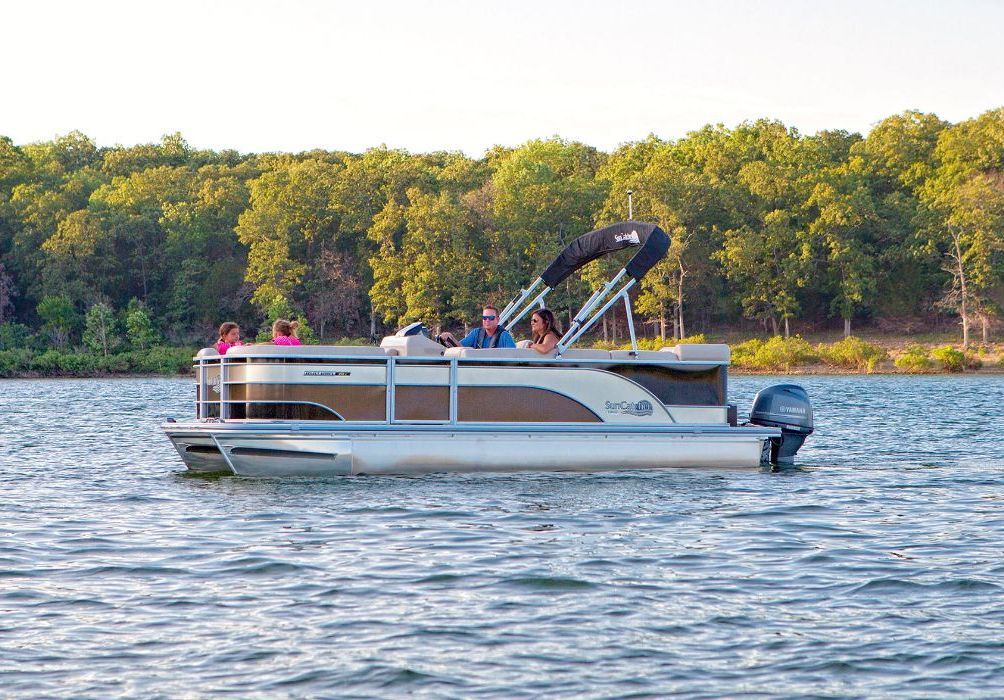 A group of people are riding a pontoon boat on a lake.