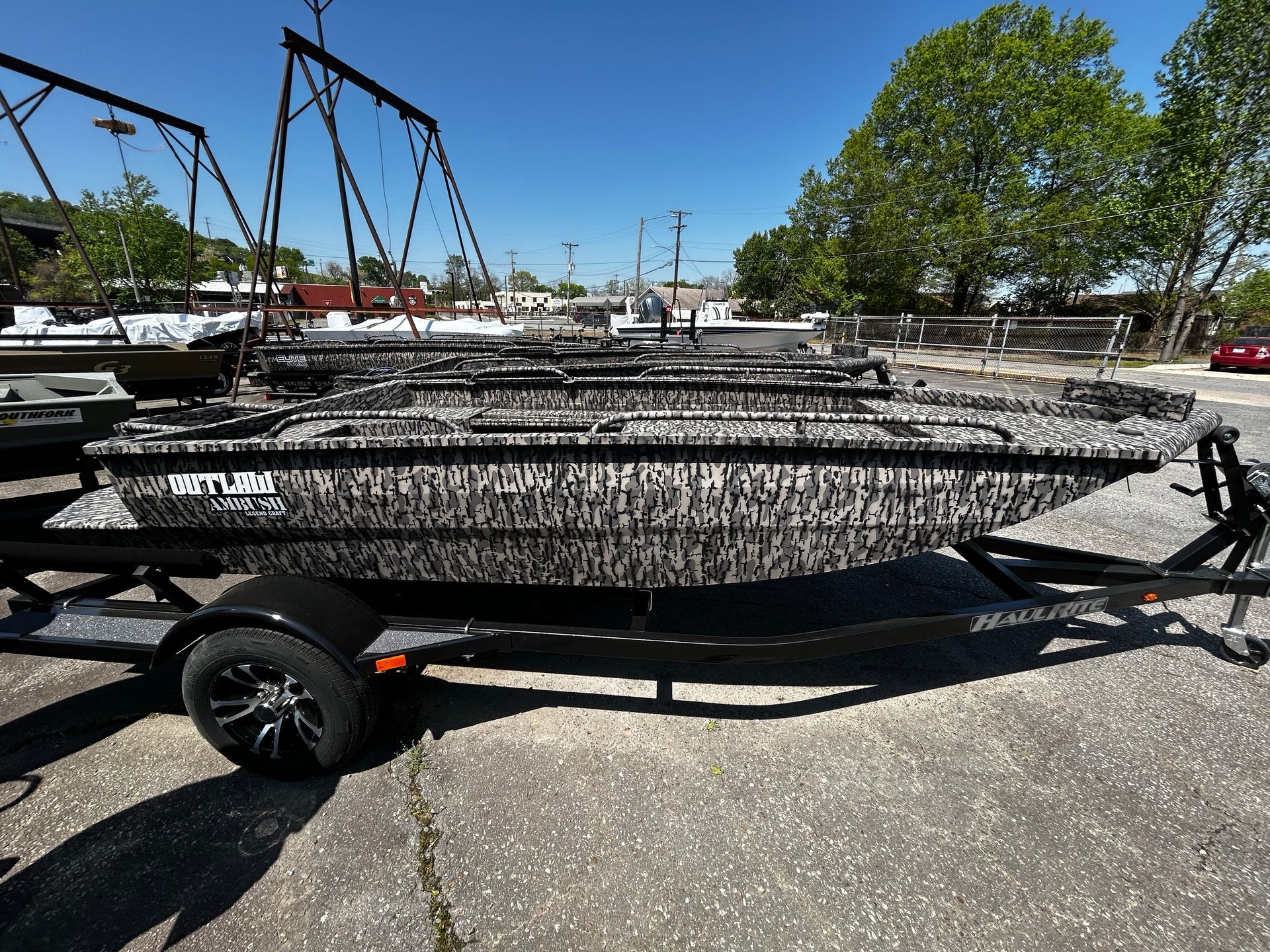 A boat on a trailer is parked in front of a arts marine store.