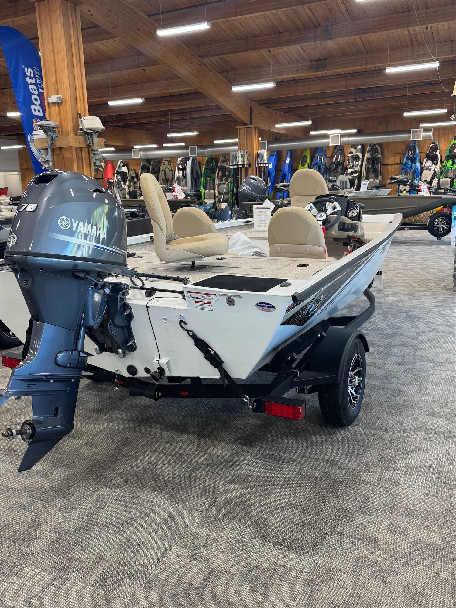 White fishing boat with tan seats and a Yamaha motor, indoors at a store.