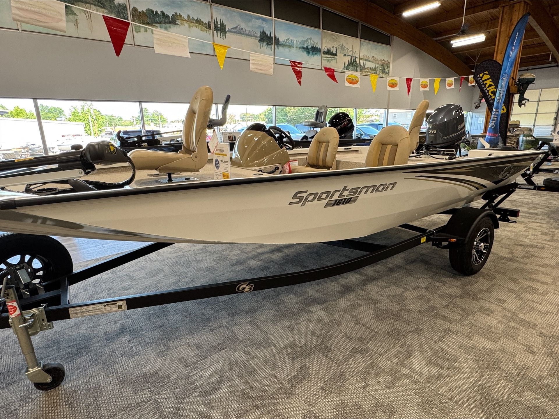 A white and gray Sportsman fishing boat on a trailer inside a showroom.