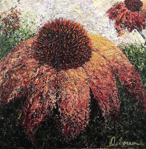 Close-up of a giant orange and red flower with a textured, detailed surface, surrounded by green foliage.