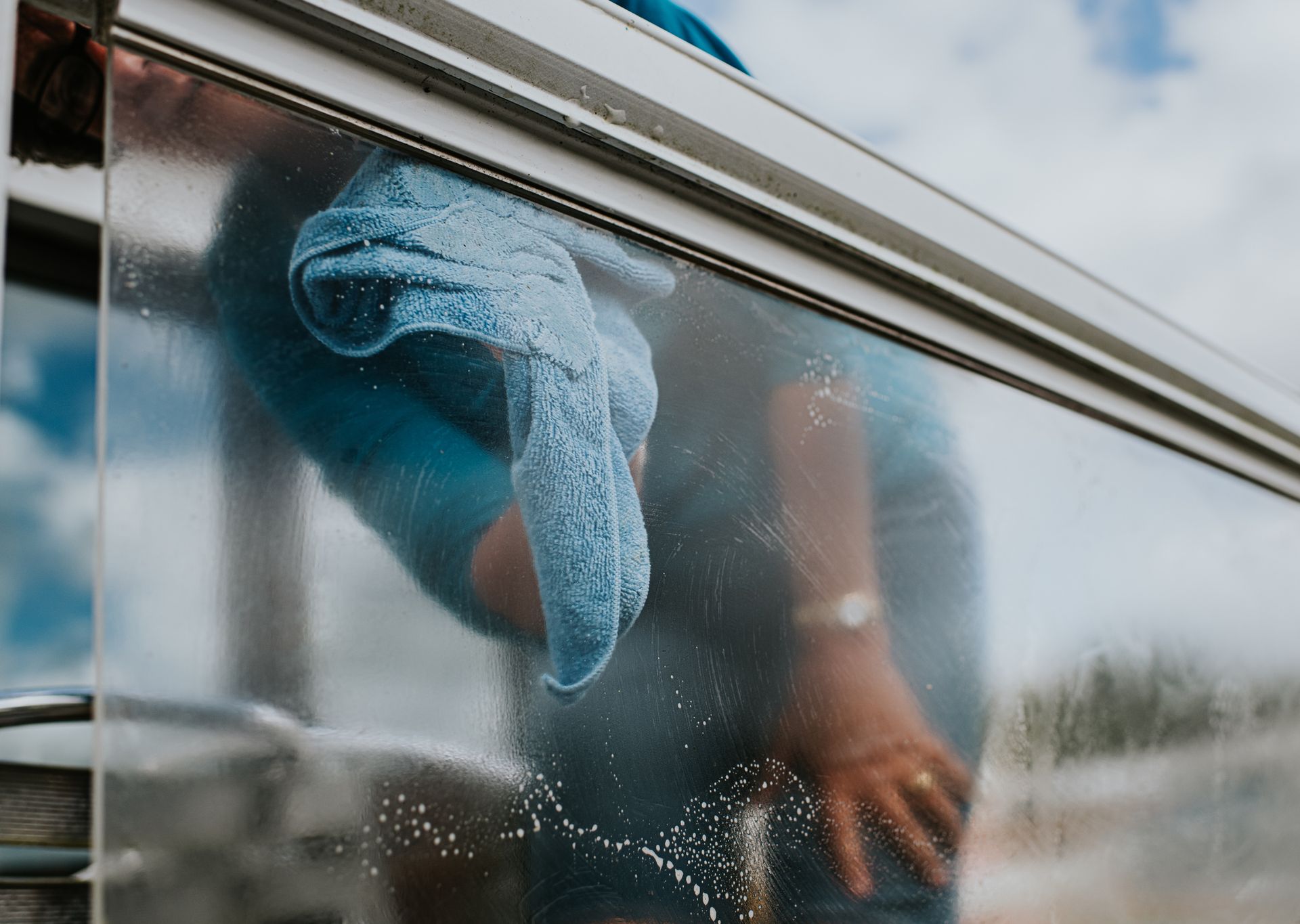 Person wiping a window with a blue cloth.