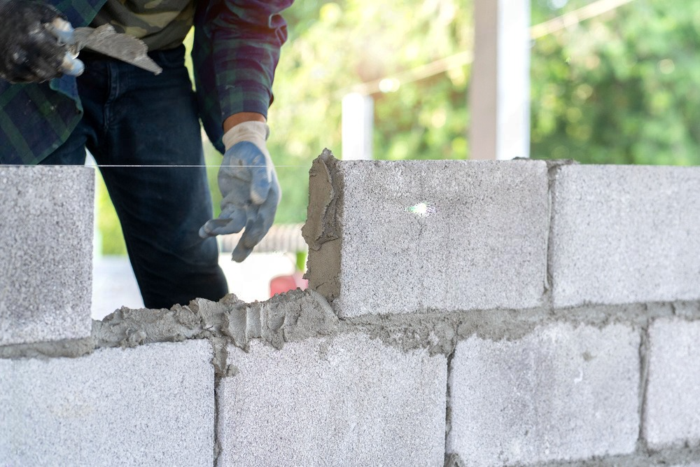 a man is laying bricks on a wall .