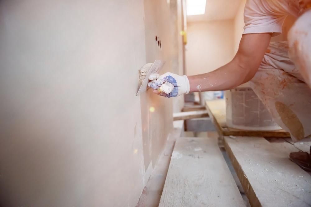 a woman is plastering a wall with a trowel .