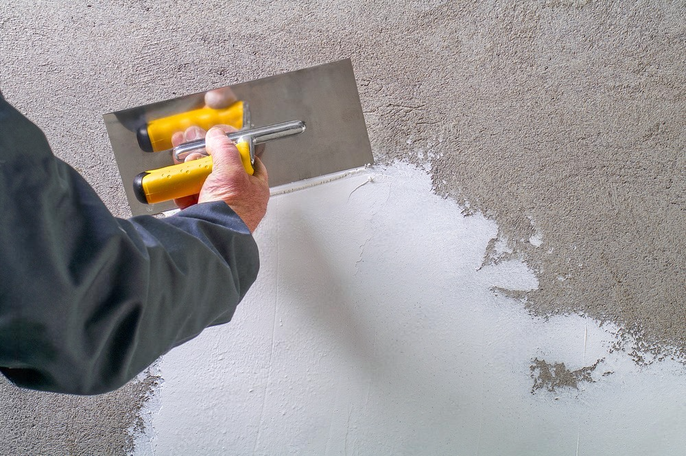 a person is plastering a wall with a trowel .