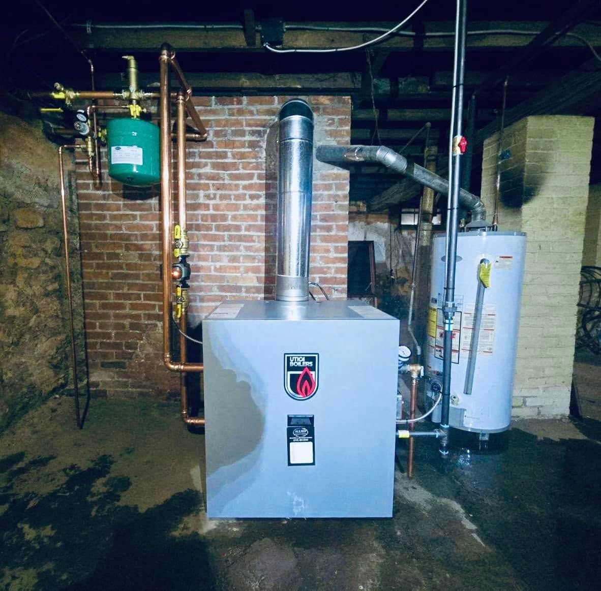 Boiler room with metal furnace, ductwork, and water heater against brick walls
