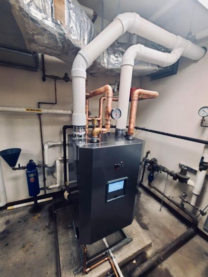 Industrial boiler system with copper and white pipes in a utility room
