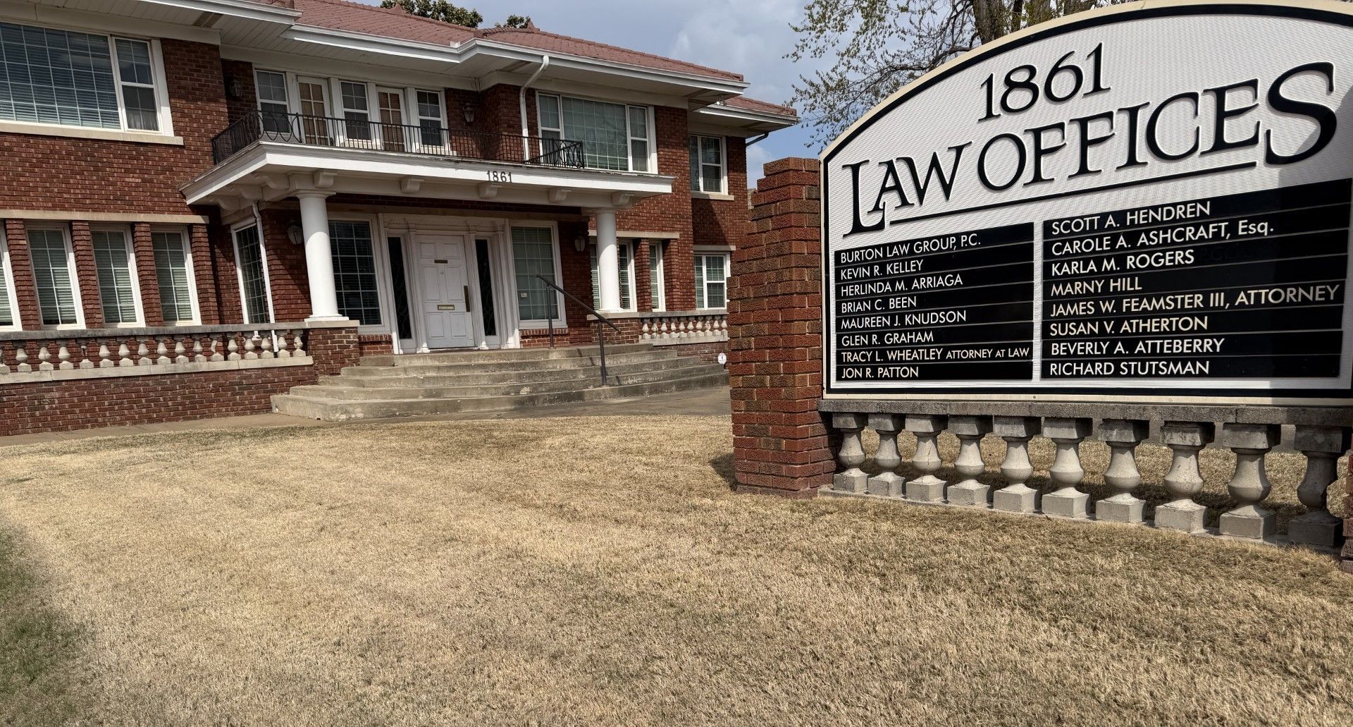 Brick law office building with a large sign reading “1861 LAW OFFICES” in front of it.