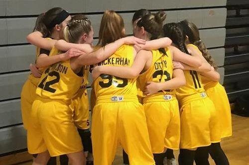 Basketball team in yellow jerseys huddling together on a gym court