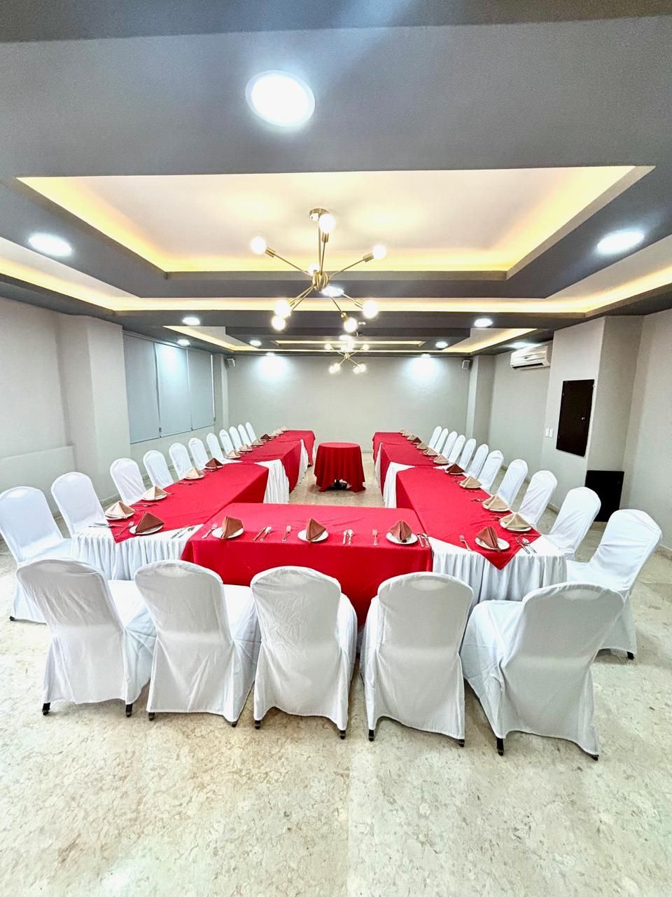 Una sala grande con mesas y sillas preparadas para una reunión.
