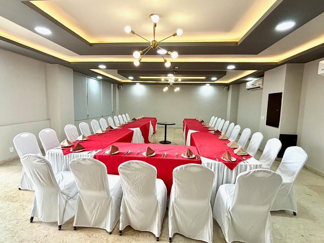 Una sala grande con mesas y sillas preparadas para una reunión.